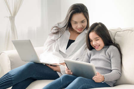 happy mother and daughter with laptop and tablet pcの写真素材
