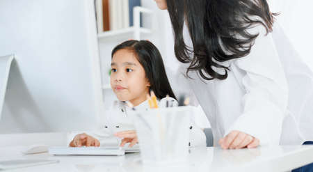 happy Little girl looking at computer with her motherの写真素材
