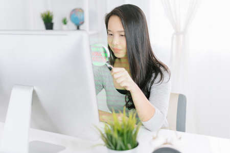woman with magnifier glass examining a desktop computer .Scanning Files Searching Processing Anti-virus Conceptの写真素材