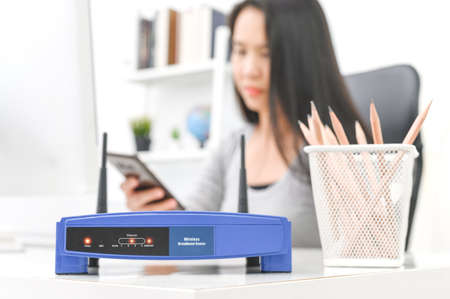Wireless router and woman using a smartphone  in office. router wireless broadband home laptop computer phone wifi conceptの写真素材