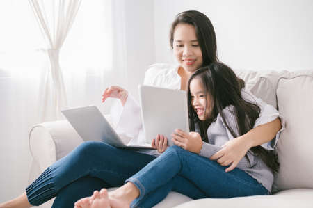 happy mother and daughter with laptop and tablet pcの写真素材