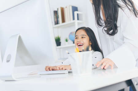 happy Little girl looking at computer with her motherの写真素材
