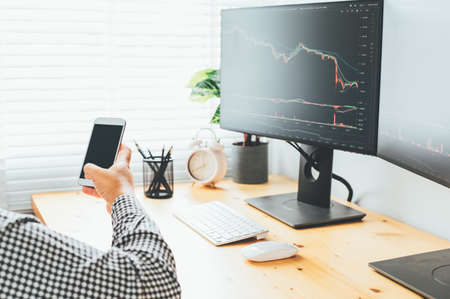 Over the shoulder view of and stock broker trading online while accepting orders by phone.の写真素材