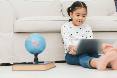 Happy Asian girl using laptop computer, concept for kid's art and home school.の写真素材