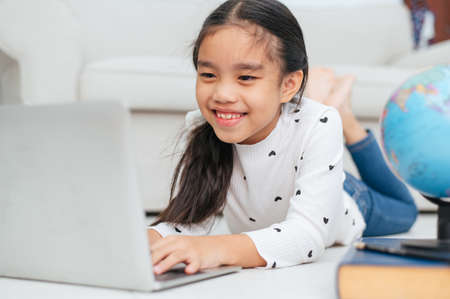 Happy Asian girl using laptop computer, concept for kid's art and home school.の写真素材