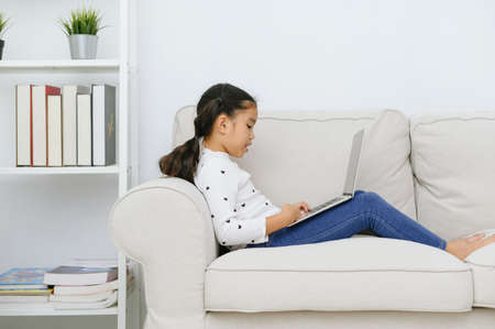 Happy Asian girl using laptop computer, concept for kid's art and home school.の写真素材