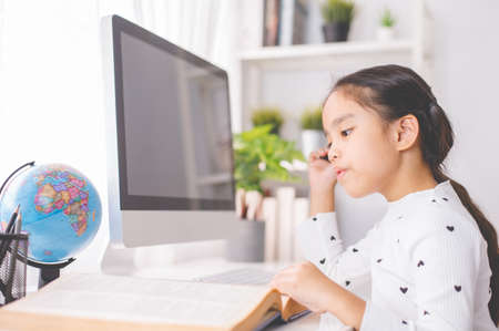 happy beautiful little girl student  using mobile pad computer studying through online e-learning systemの写真素材