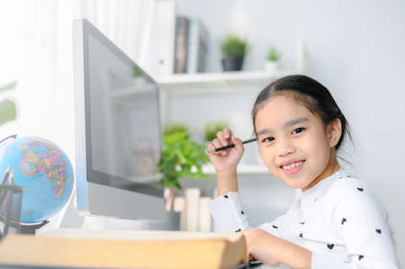 happy beautiful little girl student  using mobile pad computer studying through online e-learning systemの写真素材