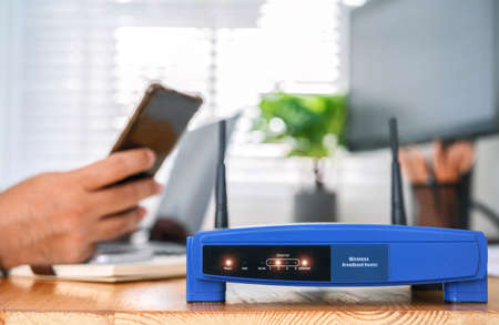 closeup of a wireless router and a man using smartphone on living room at home officeの写真素材