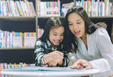 Happy mother and daughter  reading book together. Mother and daughter reading book togetherの写真素材
