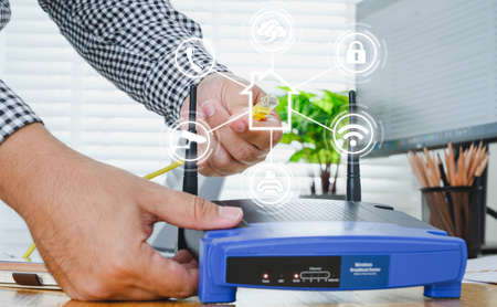 Man plugs internet cable into the router. router wireless wire broadband home conceptの写真素材