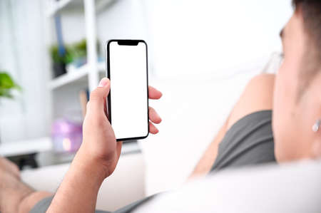 man hands holding phone with isolated screen on the sofa in the roomの写真素材