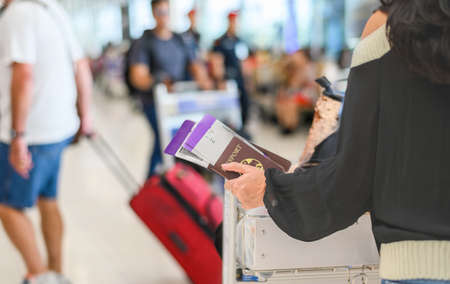 Closeup of girl holding passport and boarding pass at airportの写真素材