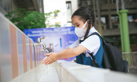 Asian student  washing hands at the outdoor wash basin in the school. Preventing Contagious diseases, Plague. Kids health, protecting the virus Covid - 19 , Saving water, Cleaning, Running water.の写真素材