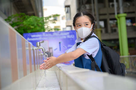 Asian student  washing hands at the outdoor wash basin in the school. Preventing Contagious diseases, Plague. Kids health, protecting the virus Covid - 19 , Saving water, Cleaning, Running water.の写真素材