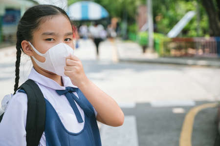 Back To School. Asian children girl wear mask to  protection for coronavirus(covid-19) in the school . Portrait of Thai student wearing protection mask bad weathe. infection control concept.の写真素材