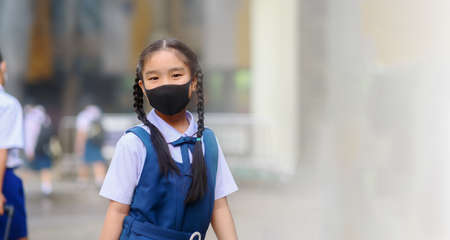 Back To School. Asian children girl wear mask to  protection in prevention for coronavirus(covid-19) in the school . Portrait of Thai student wearing protection mask bad weathe. Protection against virus and infection control concept.の写真素材