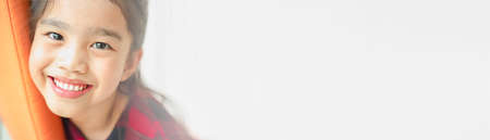 Smiling beautiful Asian kisd  with perfect smile and white teeth  in clinic, panoramic banner with copy spaceの写真素材