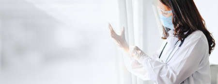 Doctor preparing for the surgical operation and wearing protective glasses for Fighting Covid-19 (Corona virus) with white background Coronavirus outbreak or Covid-19, panoramic banner with copy spaceの写真素材