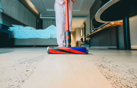 Modern vacuum cleaner while vacuuming. woman using a vacuum cleaner while cleaning carpet in the house.  House cleaning concept.の写真素材