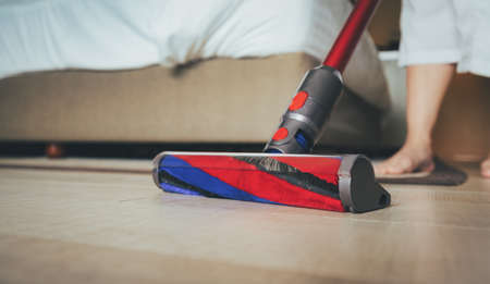 Modern vacuum cleaner while vacuuming. woman using a vacuum cleaner while cleaning carpet in the...