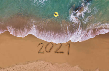 Happy New Year 2021, lettering on the beach with wave and blue sea. Numbers 2021 year on the sea shore, New Years concept.の写真素材