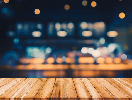 wooden table in front of abstract blurred restaurant lights backgroundの写真素材