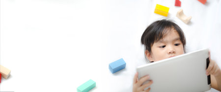a little girl down playing mobile games on the tablet. Learning, education and communication on the Internet using. banner background with copy spaceの写真素材