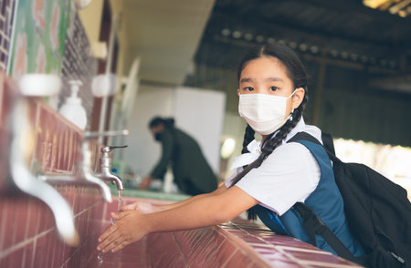 Asian student washing hands at the outdoor wash basin in the school. Preventing Contagious diseases, Plague. Kids health, protecting the virus Covid - 19 , Saving water, Cleaning, Running water.の写真素材