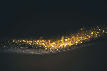 Gold glitter texture on a black background. Golden grainy abstract texture on a black background. Design element.の写真素材