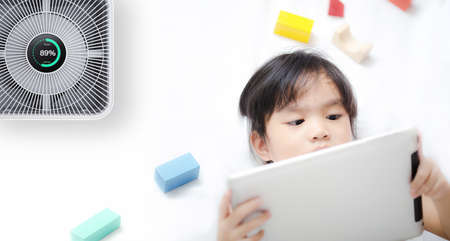 Little girl using tablet in room with modern air purifierの写真素材