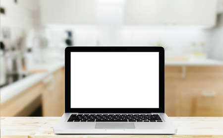 Modern computer,laptop with blank screen on Wood table top on blurred kitchen backgroundの写真素材