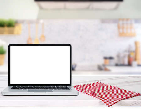 Modern computer,laptop with blank screen on Wood table top on blurred kitchen backgroundの写真素材