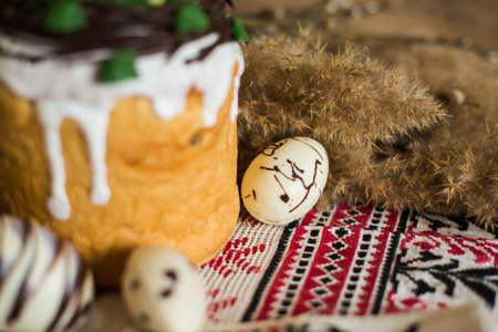 Easter pie in eco-style decorated in the form of a nest with eggs on the background of the national traditional towelの写真素材