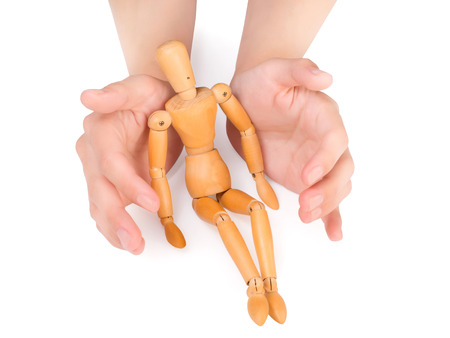 female hands covering wooden man isolated on white with clipping pathの写真素材