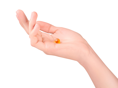 Female hand holding orange gelatin capsule isolated on white with clipping pathの写真素材