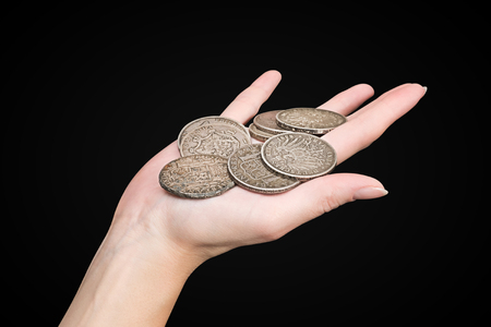Female hand with different old coins isolated on black background with clipping pathの写真素材