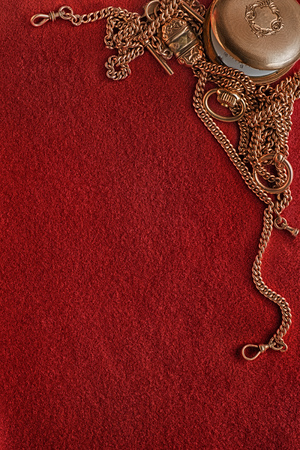 Red felt background and composition with ancient golden watch and chains as frameの写真素材