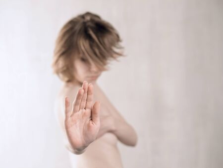 Partially nude woman with stop gesture. Selective focus on hand. Sexual denial, estrangement or break up conceptの写真素材