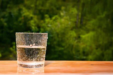 Wet drinking glass with water on green wood backgroundの写真素材