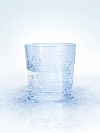 Wet glass of water with drops on abstract blue backgroundの写真素材