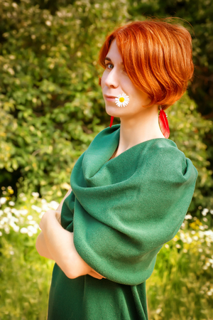 Outdoor portrait of red-headed woman in green dress at bright summer backgroundの写真素材