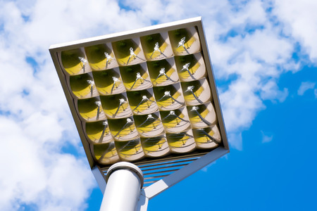 Outdoor faceted illumination reflector with ground reflection against the sky. Park or sports objects lighting equipmentの写真素材