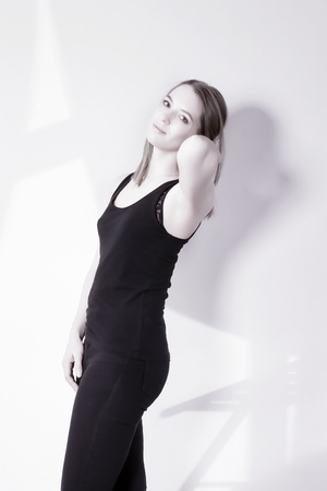 Young woman in casual against white wall with home interior shadows. Cold toned high key imageの写真素材
