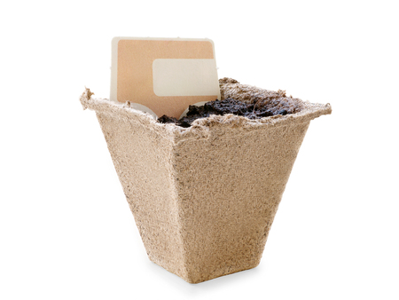 Small peat pot filled by soil with blank label. Copy space on the label. Isolated on white, clipping path includedの写真素材