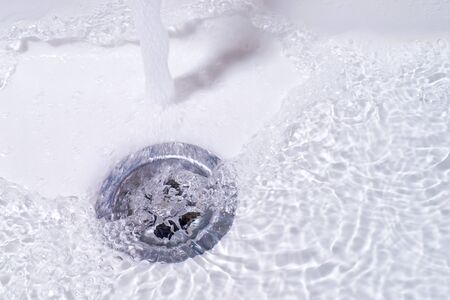 Water running down in the drain. Bathroom sink close upの写真素材
