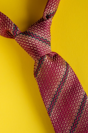 Classic brown striped tie knot close up on yellow background. Man style conceptの写真素材