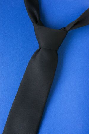 Black tie with windsor knot on blue background. Man style themeの写真素材