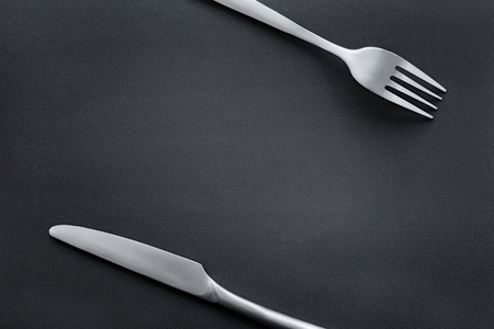 Fork and knife on black rough blackboard. Food theme template and backgroundの写真素材