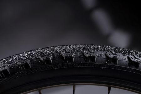 Black bike tire with water drops on abstract background. Biking themeの写真素材